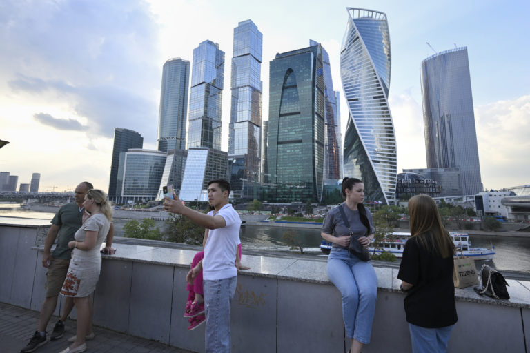 Ľudia sa v utorok 1. augusta 2023 prechádzajú na nábreží rieky Moskva v Moskve v Rusku s obchodnou štvrťou Moscow City v pozadí. Foto: TASR/AP