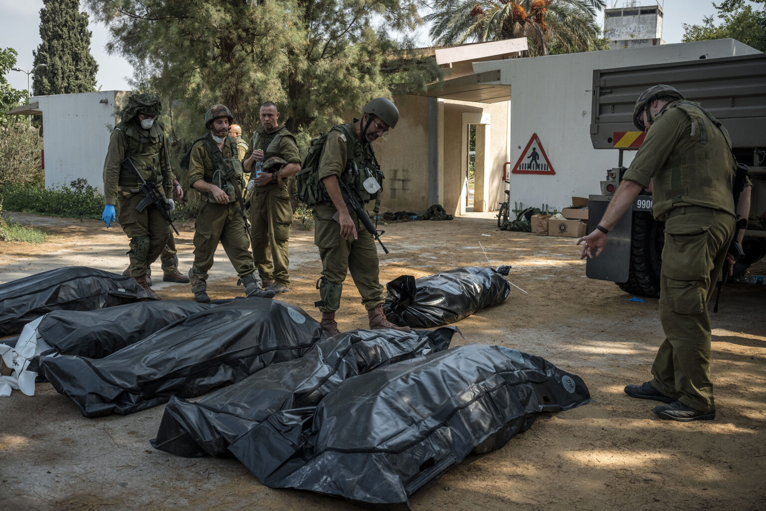 Izraelskí vojaci zbierajú telá civilistov, ktorých zabili militanti Hamasu v dedine Kfar Aza. Foto: Sergey Ponomarev pre New York Times