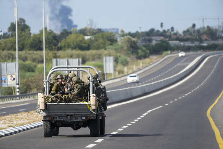 Izraelskí vojaci smerujú  k horiacemu miestu po raketovom útoku. Foto: TASR/AP 
