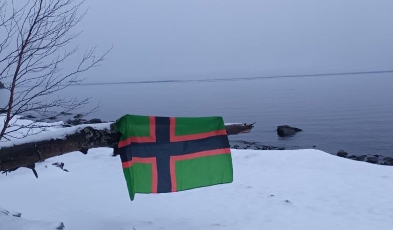 Vlajka Karelského národného hnutia, v pozadí typická karelská príroda. Foto: sociálna sieť Telegram / t.me/Karjalan_Kansallinen_Liike