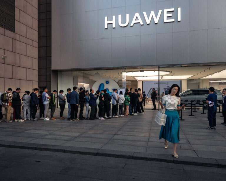 Žena výchádza z vlajkovej predajne spoločnosti Huawei. Peking, Čína. Foto: Kevin Frayer/Getty Images