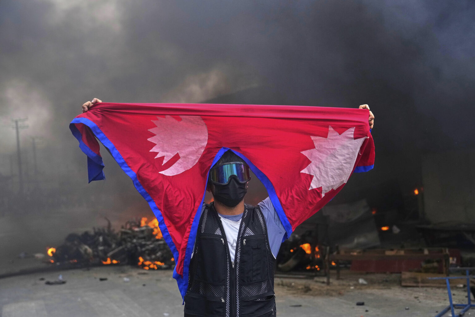 Muž s nepálskou vlajkou po tom, ako demonštranti počas protestu proti nepálskej vláde podpálili policajnú stanicu v Káthmandu. Foto: TASR/AP

