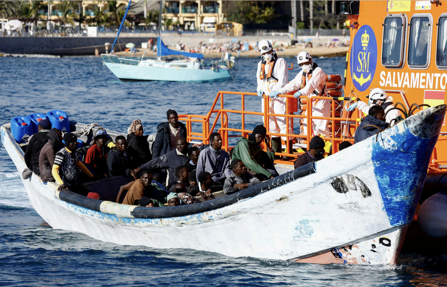Plavidlo španielskej pobrežnej stráže ťahá čln s migrantmi na palube. Foto: REUTERS/Borja Suarez