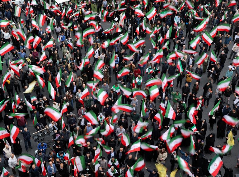 A crowd waves Iranian flags during a public gathering. Photo: Majid Asgaripour/WANA/Reuters