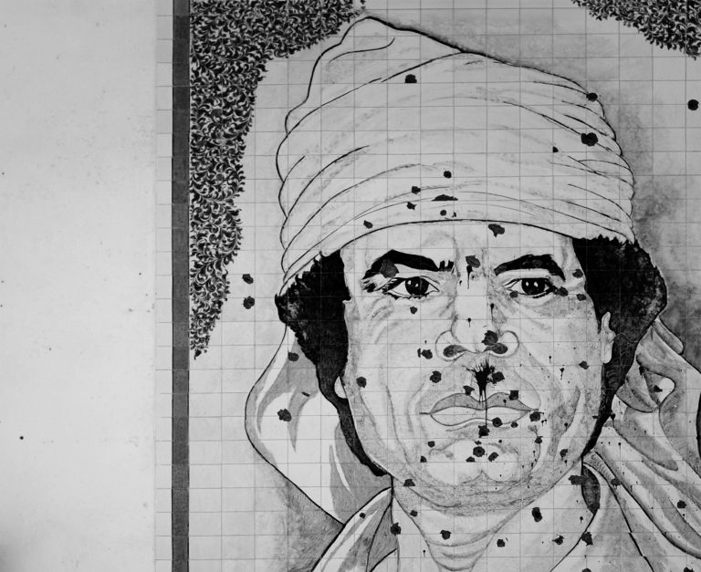 Mozaika zobrazujúca bývalého líbyjského vodcu Muammara Kaddáfího na stene budovy posiatej stopami po guľkách. Foto: Daniel Berehulak/Getty Images 