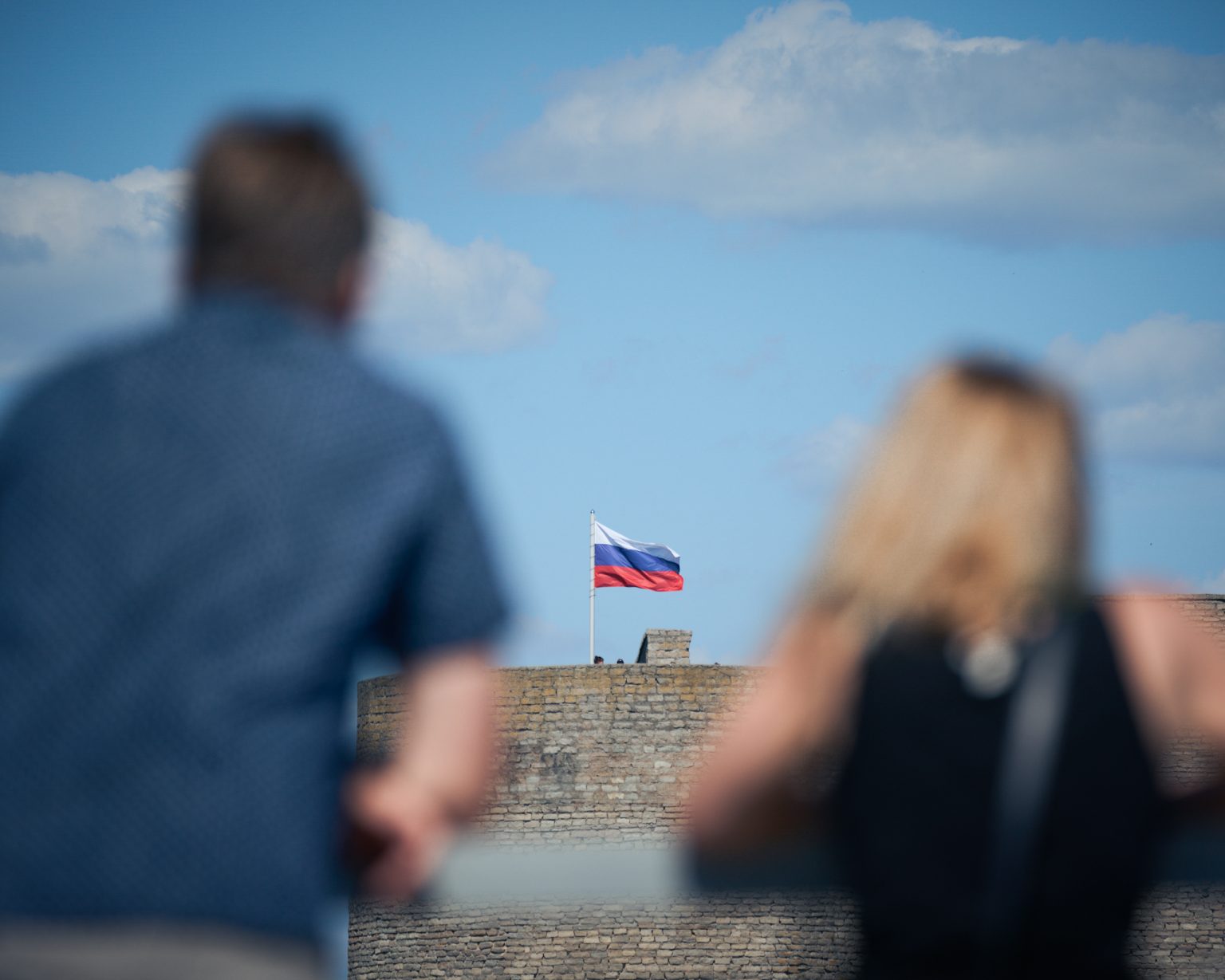 Onlookers watch as the Russian flag flies over Ivangorod Fortress across the border from Narva, one of the last remaining crossing points between Estonia and Russia. Photo: Jaap Arriens/NurPhoto/Getty Images