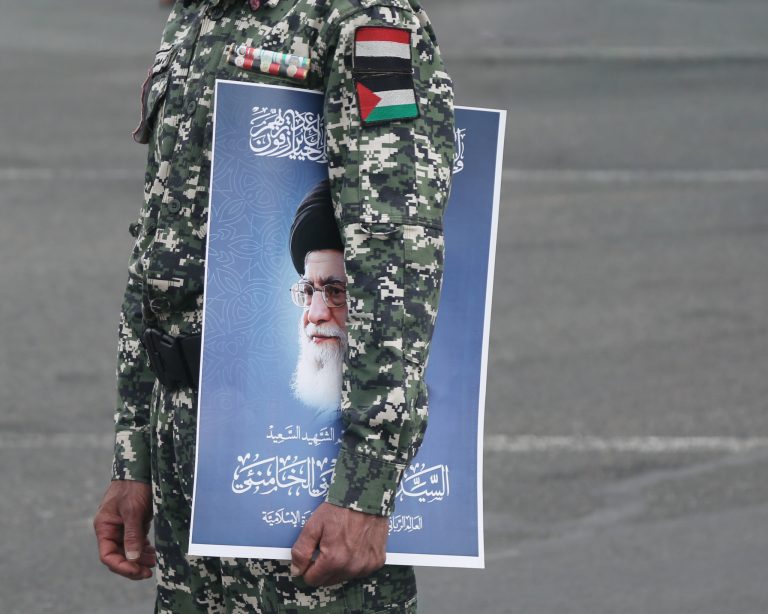 Bezpečnostný vojak drží plagát s podobizňou iránskeho najvyššieho vodcu Alího Hosseiního Chameneího. Foto: Mohammed Hamoud/Getty Images