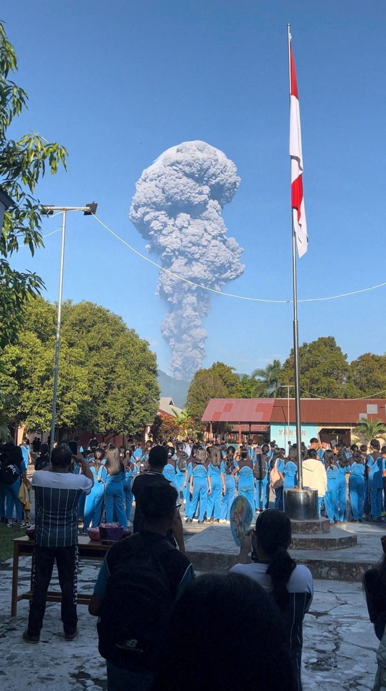 Ľudia sledujú dym stúpajúci po erupcii hory Dukono.