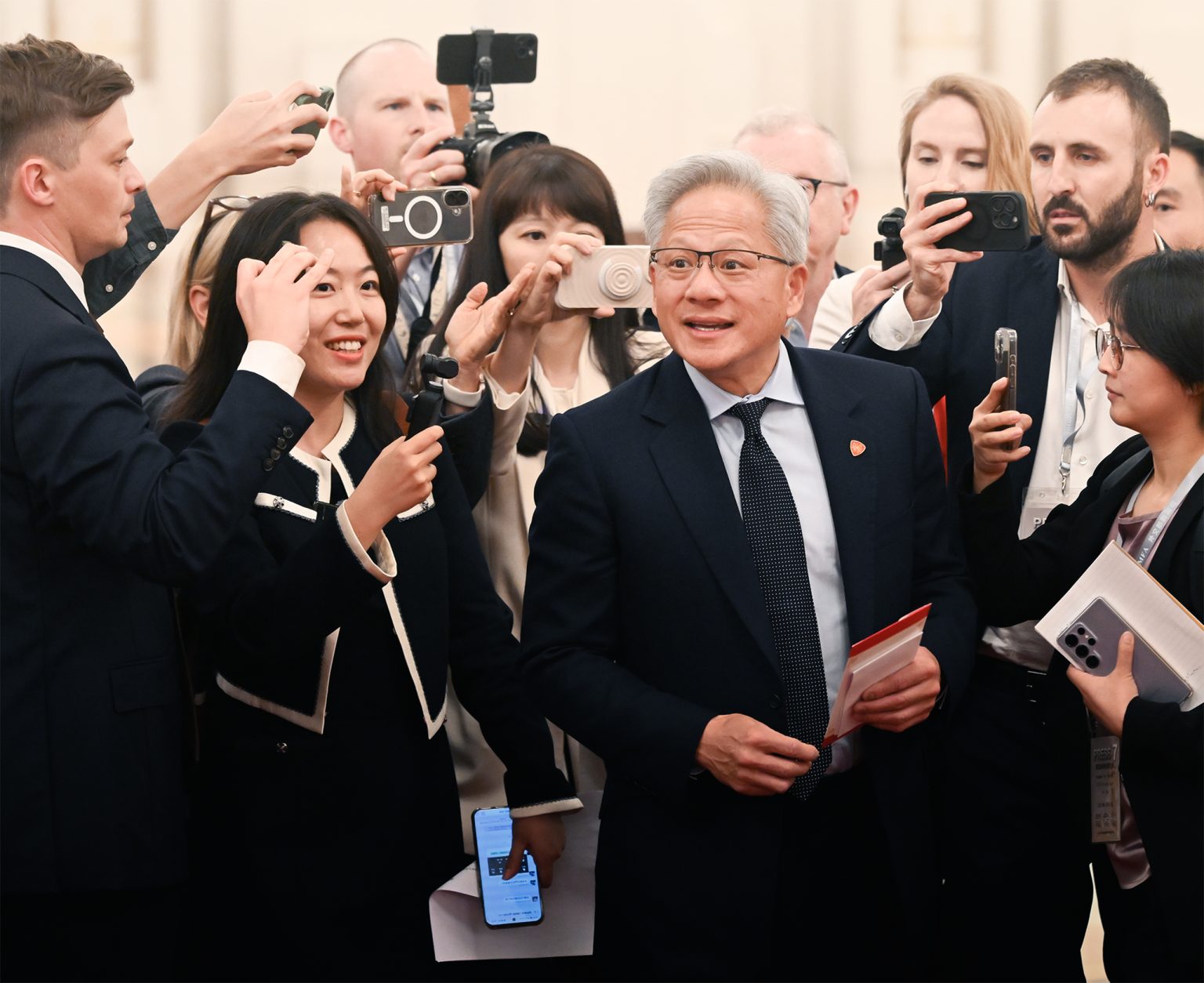 Jensen Huang obklopený fotografmi v Pekingu.