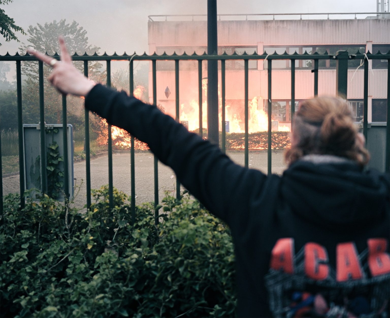 A demonstrator flashes a victory sign near a fire at the asylum center in Loosdrecht. The unrest has pushed migration back into the Dutch national spotlight. Photo: Georgios Kostomitsopoulos/NurPhoto via Getty Images