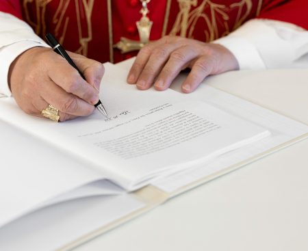 Pope Leo XIV signs a document at the Vatican.